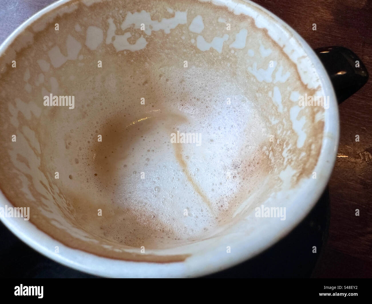 La schiuma lasciata dopo che il cappuccino è finito nel ristorante di Gothenburg, Svezia. - Immagine stock catturata con smartphone