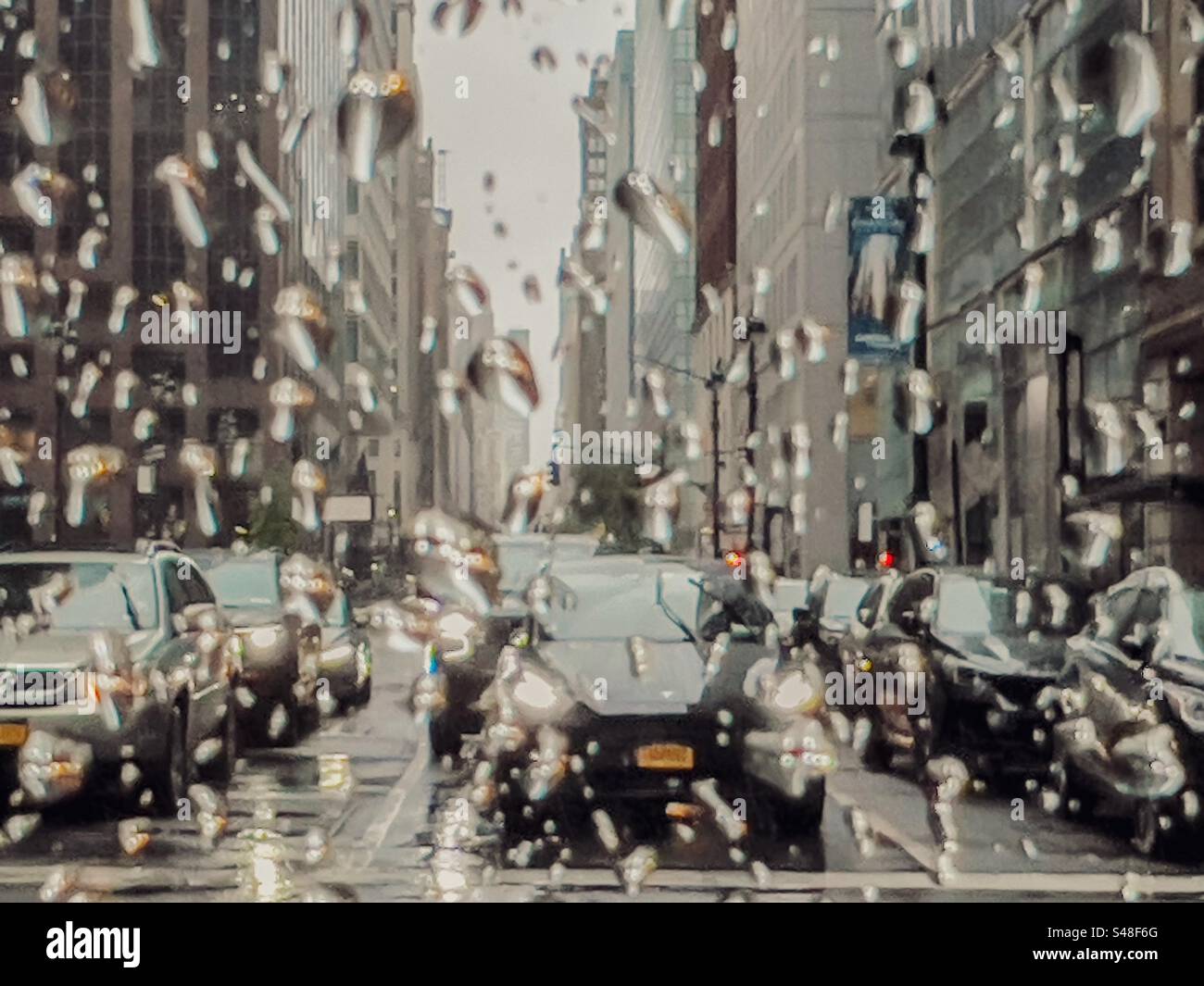 Il traffico si fermava ai semafori di New York visto attraverso una finestra che spruzzava la pioggia Foto Stock