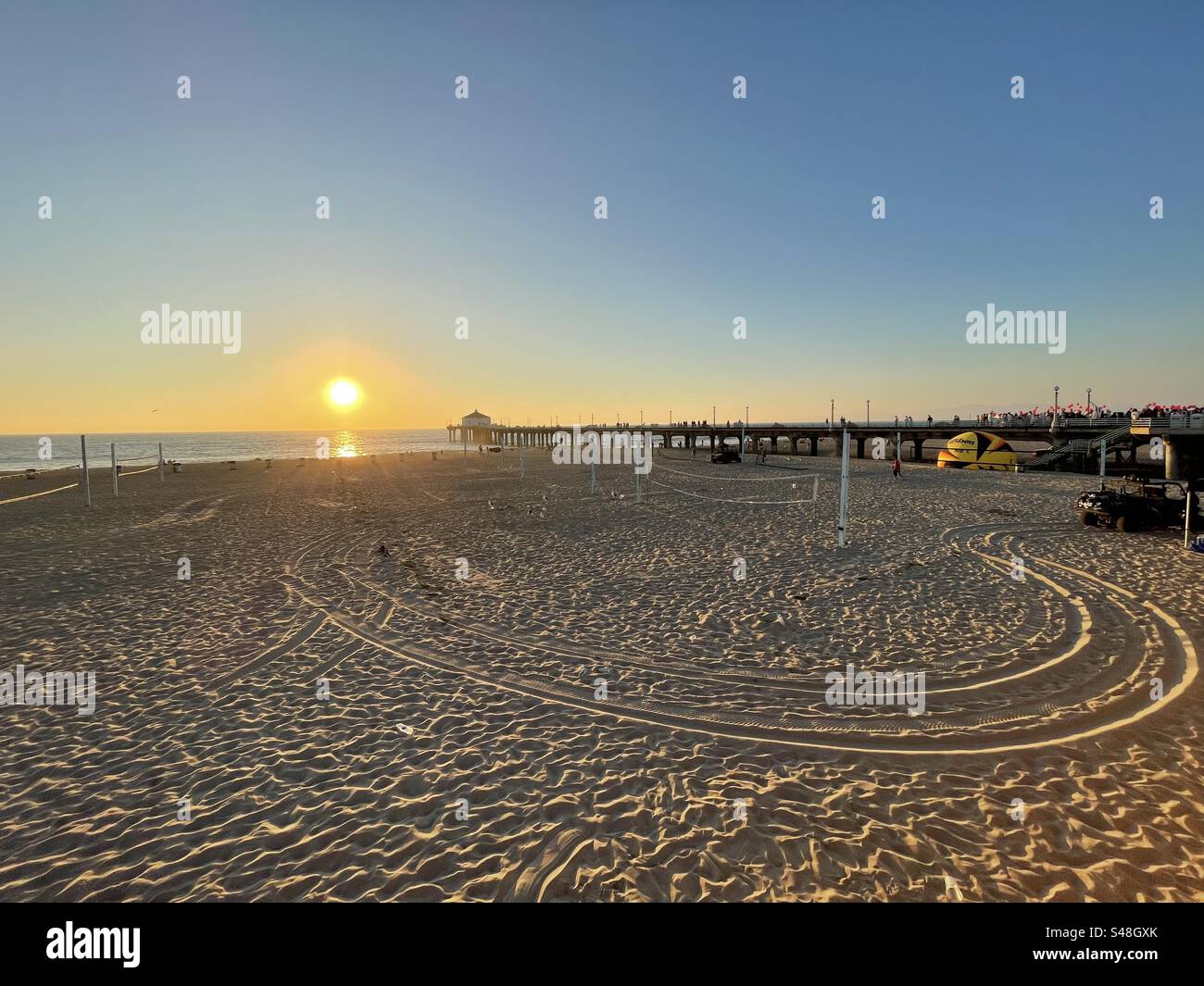 Vista grandangolare sulle piste per dune buggy, silhouette di gabbiano contro il sole, Golden Sunset, Manhattan Beach Pier, California, Orange County Foto Stock