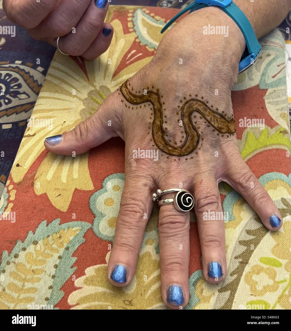 Disegno all'henné del Tamigi Londra sulla mano di una donna anziana Foto Stock