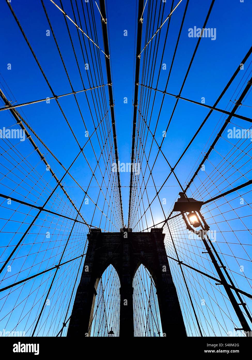 Ponte di Brooklyn e lampione in composizione simmetrica con cavi di supporto su un cielo blu brillante - Immagine stock catturata con smartphone