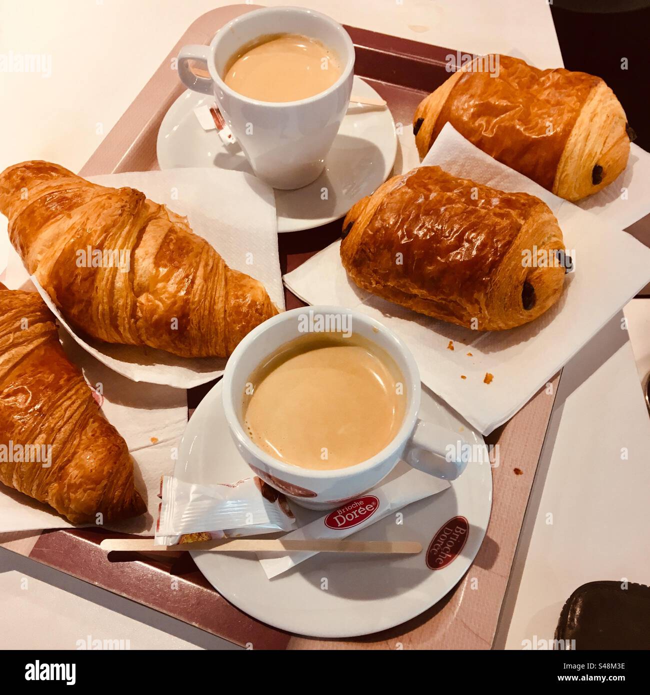 Due croissant e due croissant al cioccolato con caffè su un piatto per la colazione in un ristorante in Francia Foto Stock