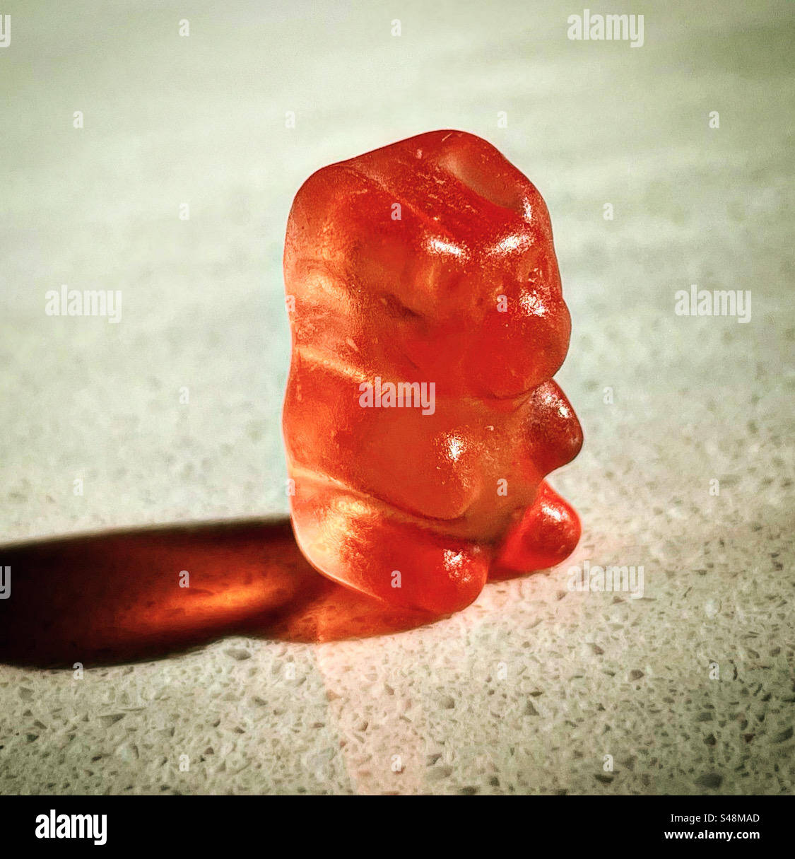 un solo orso gommoso in cucina o un negozio di caramelle sotto il sole con una texture trasparente e gommosa di colore arancione - Immagine stock catturata con smartphone