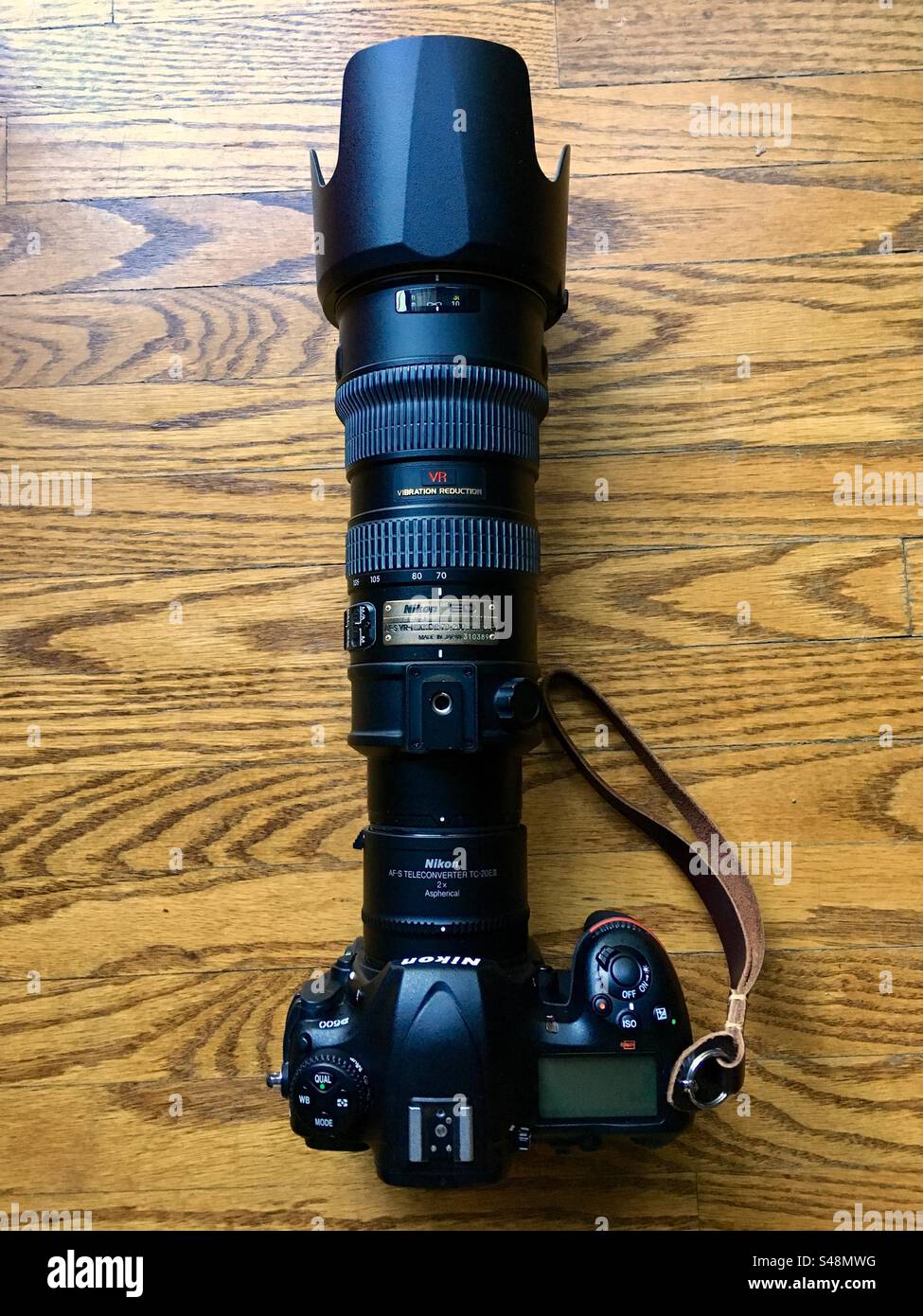 Scatto dall'alto verso il basso di una reflex digitale Nikon con teleobiettivo con zoom VR a 70-200 2,8° e raddoppio focale su sfondo in legno Foto Stock