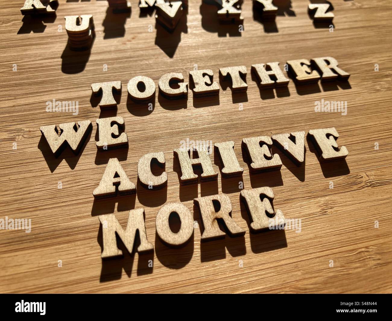 Acronimo di Together We Are More, parole motivazionali in caratteri alfabetici di legno isolati sullo sfondo - Immagine stock catturata con smartphone