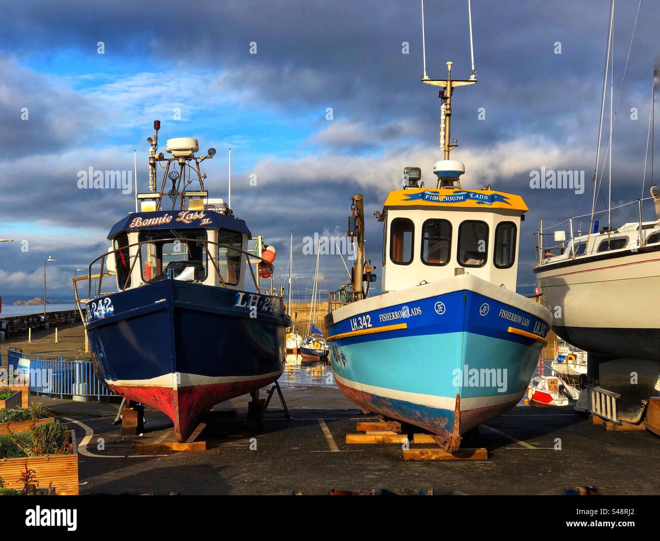 Le barche sul molo di carenaggio sono fuori servizio per manutenzione al porto di Fisherrow, Musselburgh, Scozia - Immagine stock catturata con smartphone