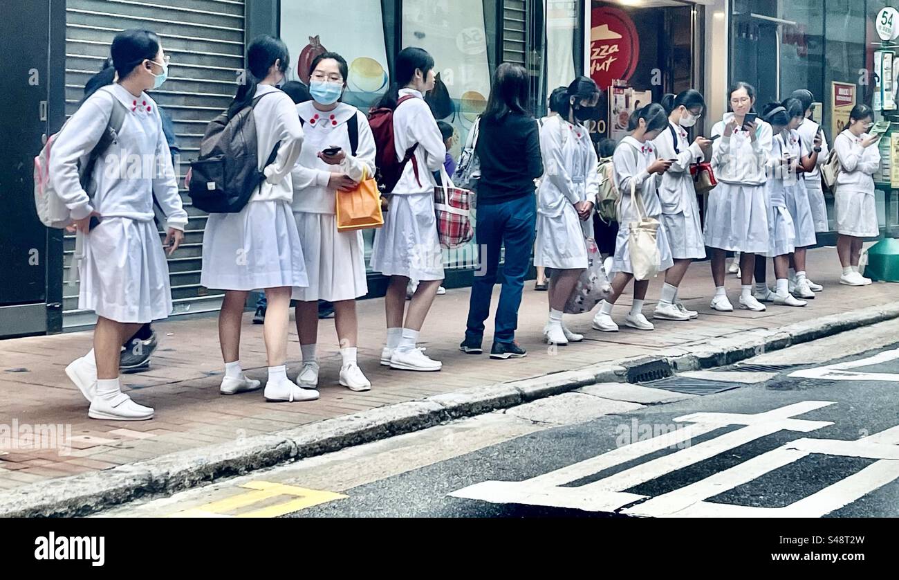 Gli studenti della scuola aspettano l'autobus. Distretto centrale, Hong Kong Foto Stock