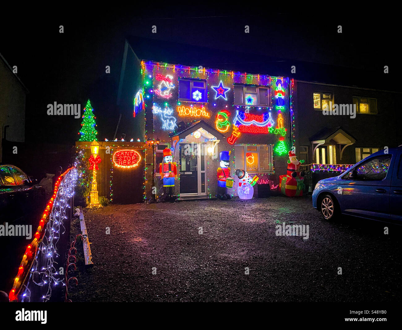 Una casa decorata con molte luminose e colorate luci natalizie e decorazioni che brillano al buio di notte. Foto Stock