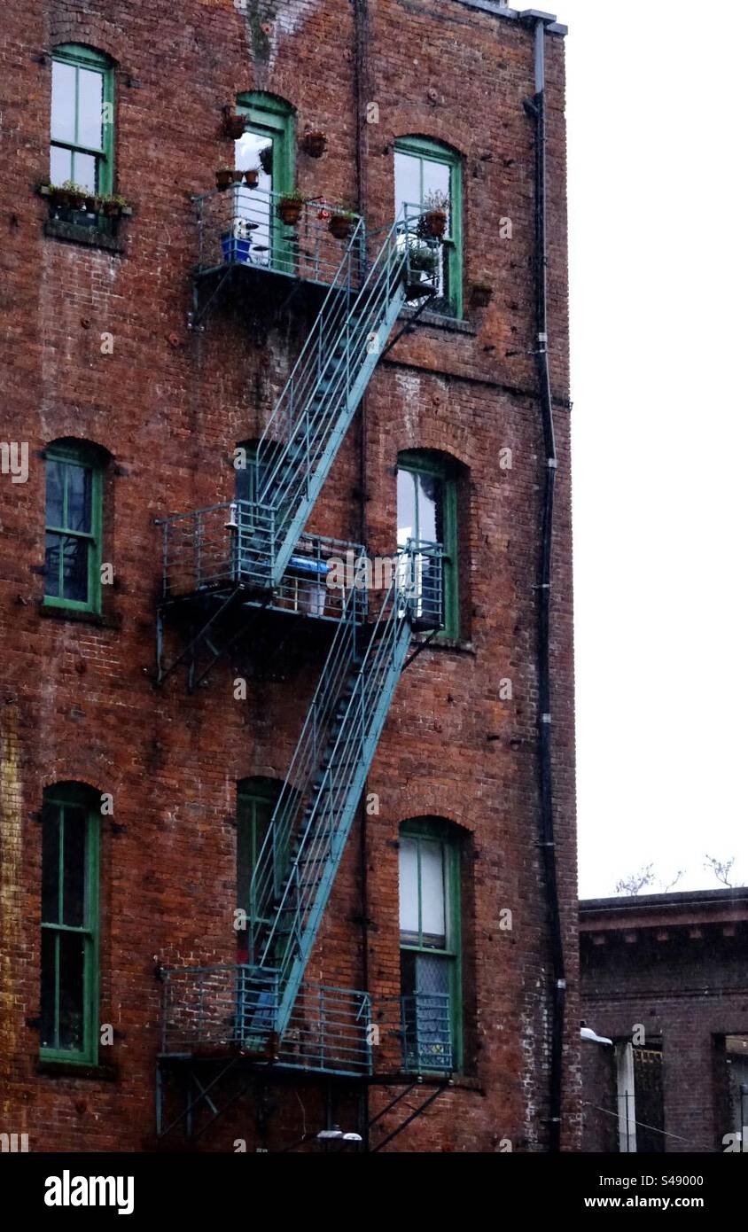 Edificio in mattoni Pioneer Square di Seattle con scale di sicurezza antincendio e finestre verdi luminose in PNW. Foto Stock
