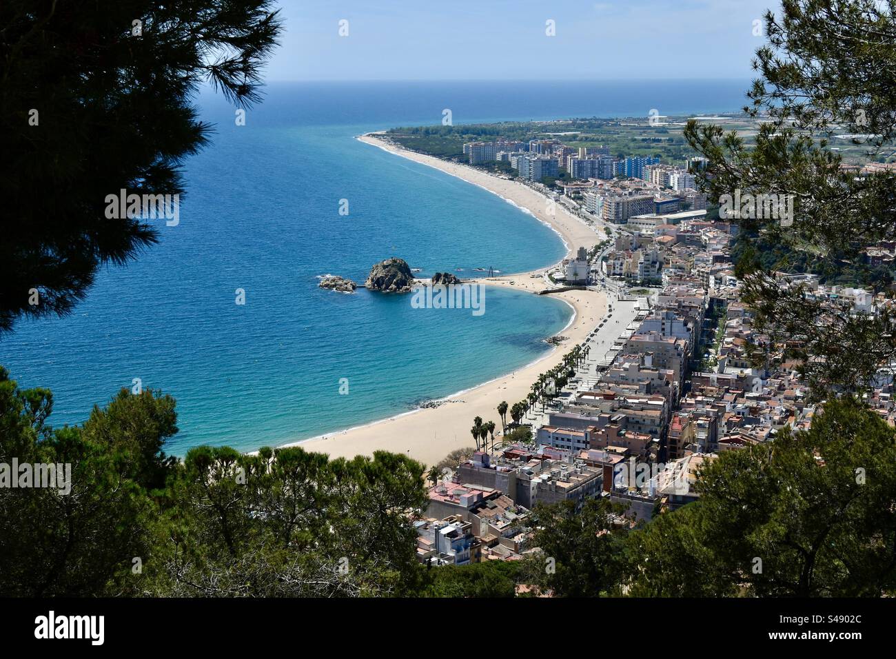 Vista sul centro di Blanes e sulla sua spiaggia principale dalla collina tra i pini. - Immagine stock catturata con smartphone