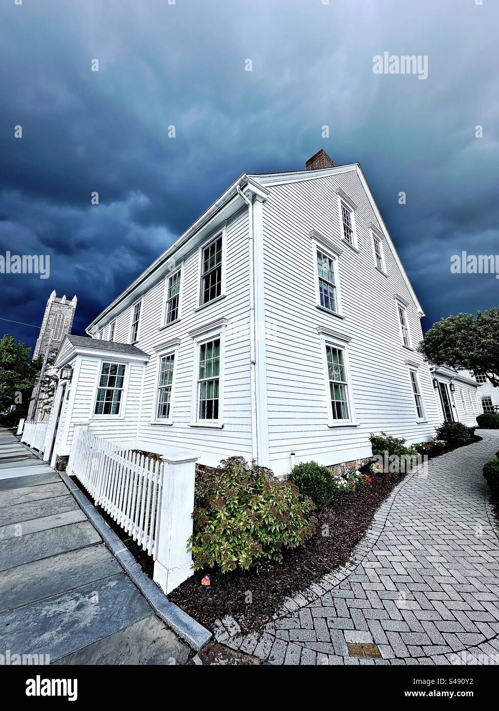 Casa bianca d'epoca restaurata a Guilford, Connecticut, USA. Cielo scuro in una giornata di pioggia. Obiettivo grandangolare. - Immagine stock catturata con smartphone