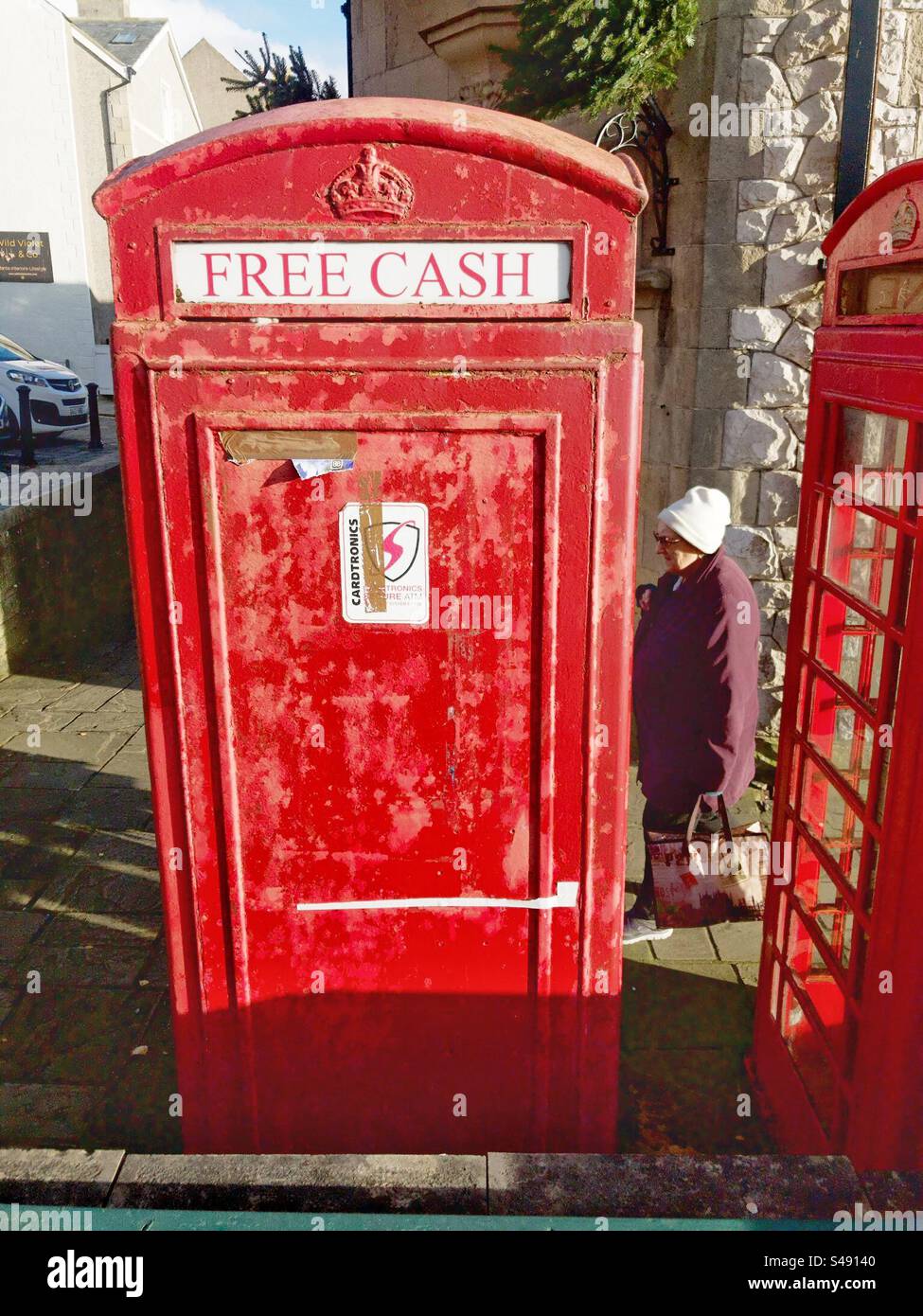 Vecchia cabina telefonica britannica trasformata in distributore di contanti sulla strada principale di Conwy, Galles del Nord. - Immagine stock catturata con smartphone