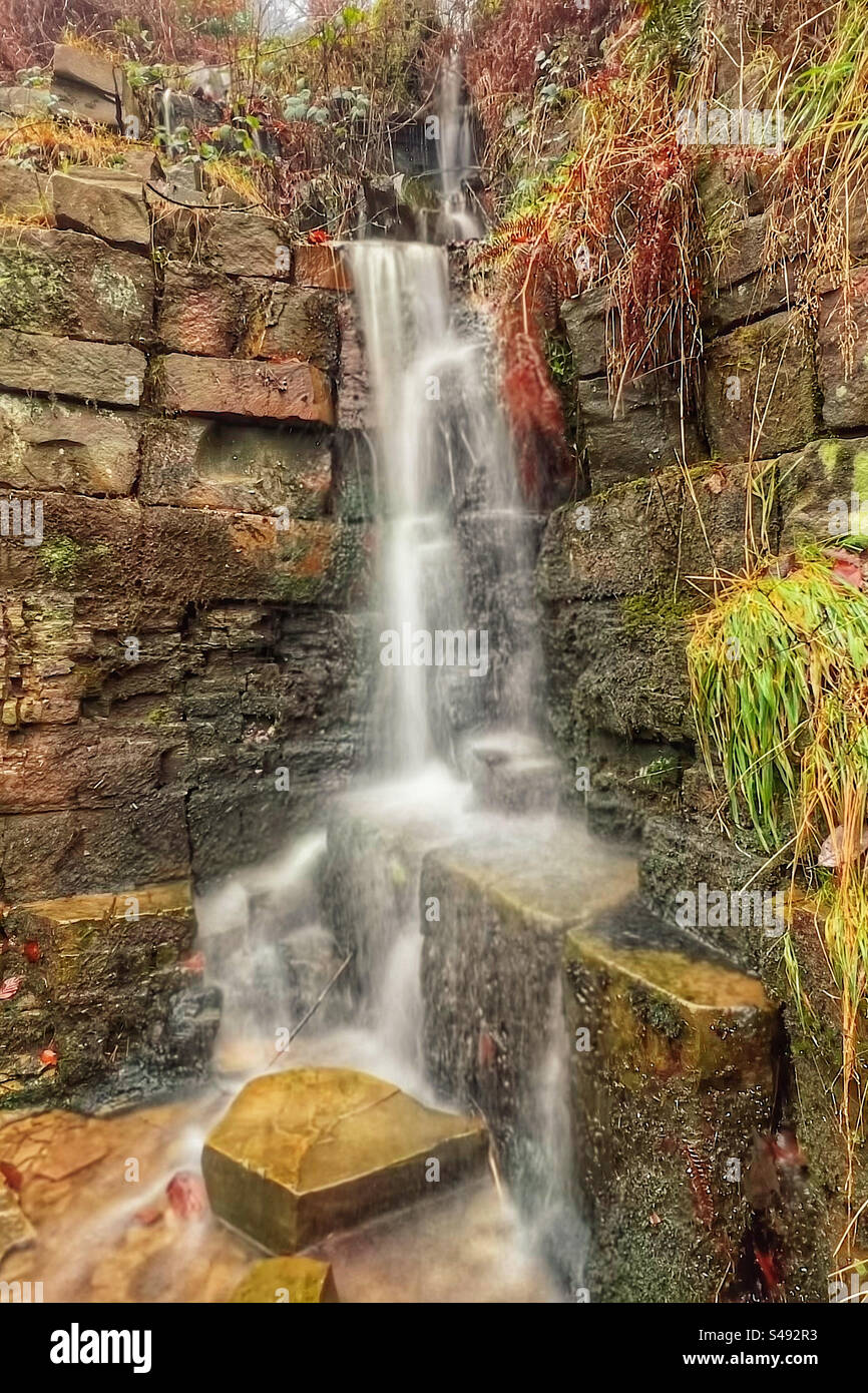 Piccola cascata a Rivington vicino a Chorley nel Lancashire. Cascata artificiale al parco a leva con acqua sfocata che mostra movimento. Foto Stock