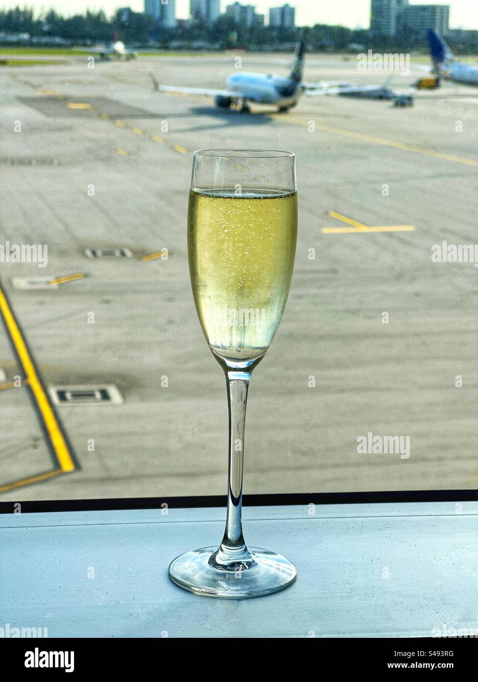 Bicchiere di champagne flute sulla finestra di una sala business dell'aeroporto. Niente persone. Foto Stock