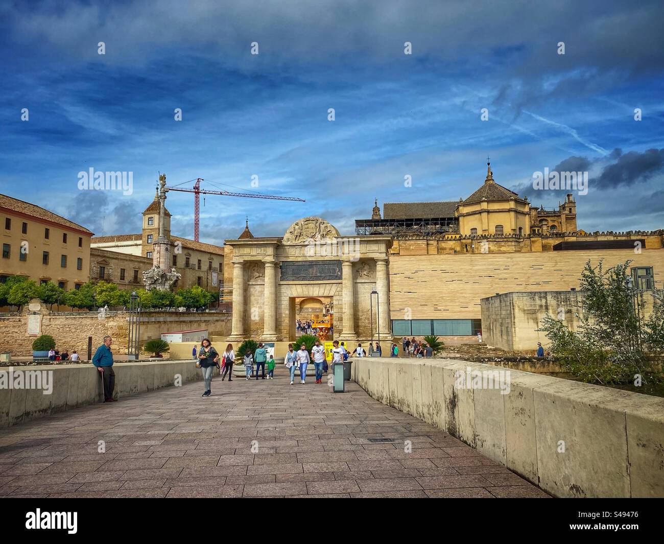 Gente che cammina sul Ponte Romano di fronte all'antica porta e agli edifici della città vecchia di Córdoba, Spagna. - Immagine stock catturata con smartphone