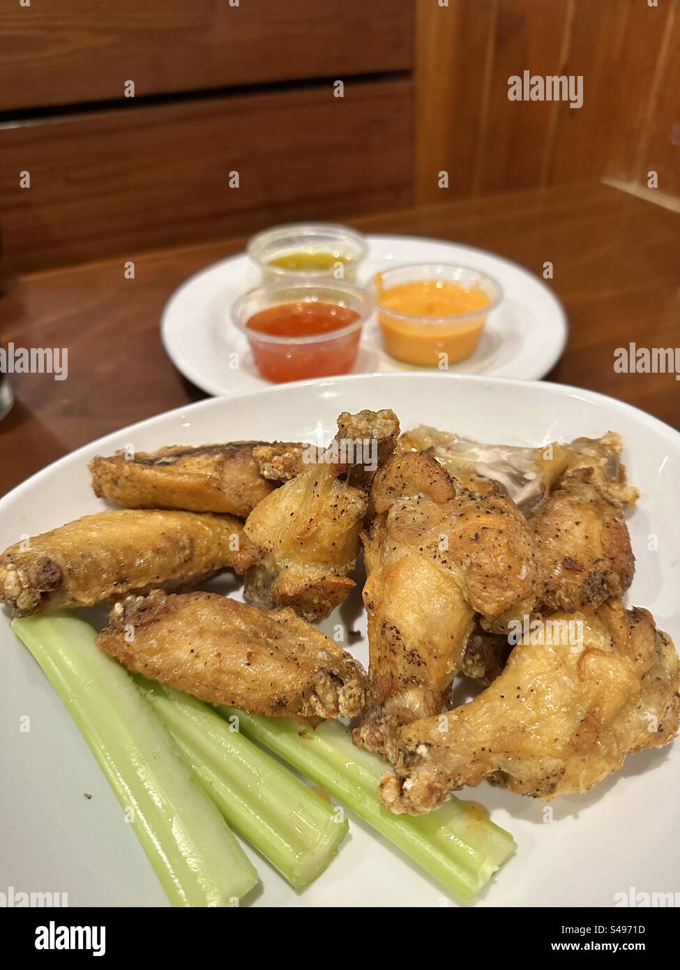 Antipasto con ali di pollo e cosce di rondine su un piatto con salse. Foto Stock