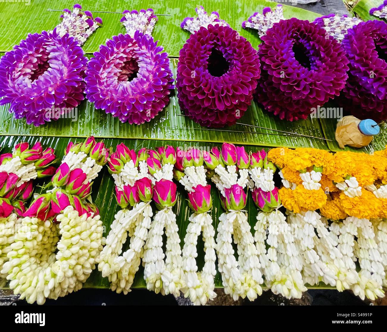 Colorate ghirlande di fiori esposte al mercato dei fiori di Pak Khlong Talat a Bangkok. Foto Stock