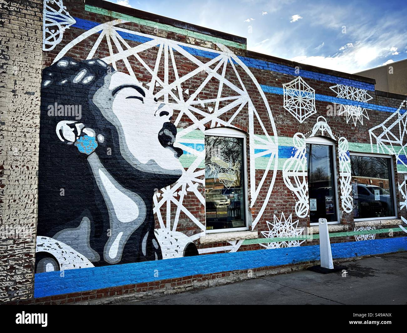 Murale di una donna con la bocca aperta e motivi geometrici intorno a lei. Situato nel centro di Loveland, Colorado, Stati Uniti. - Immagine stock catturata con smartphone
