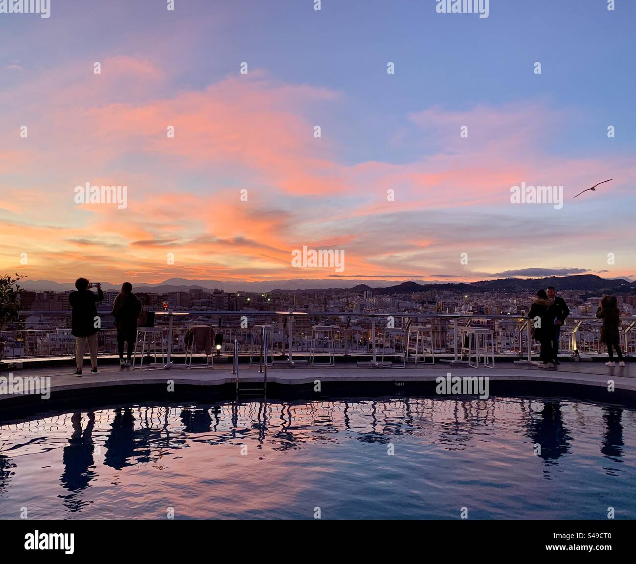 Un affascinante tramonto su Malaga, Spagna, che diffonde calde sfumature sullo skyline della città e si riflette nelle acque tranquille. Una serata idilliaca nel cuore della Costa del Sol. Foto Stock