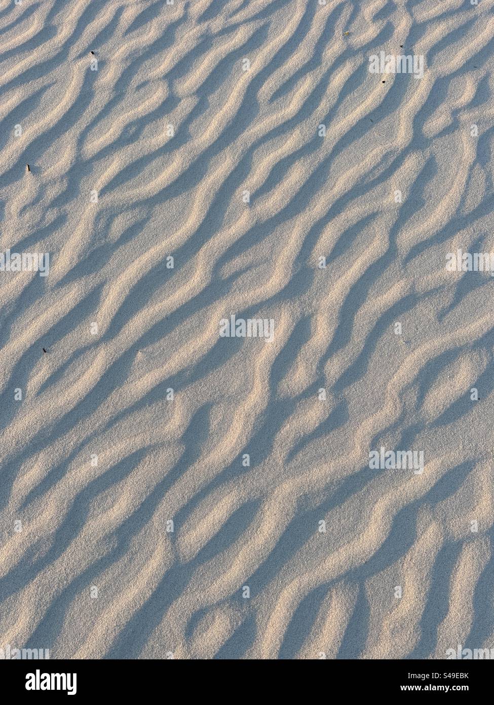 Sabbia e tessuti da spiaggia soffiati dal vento Foto Stock