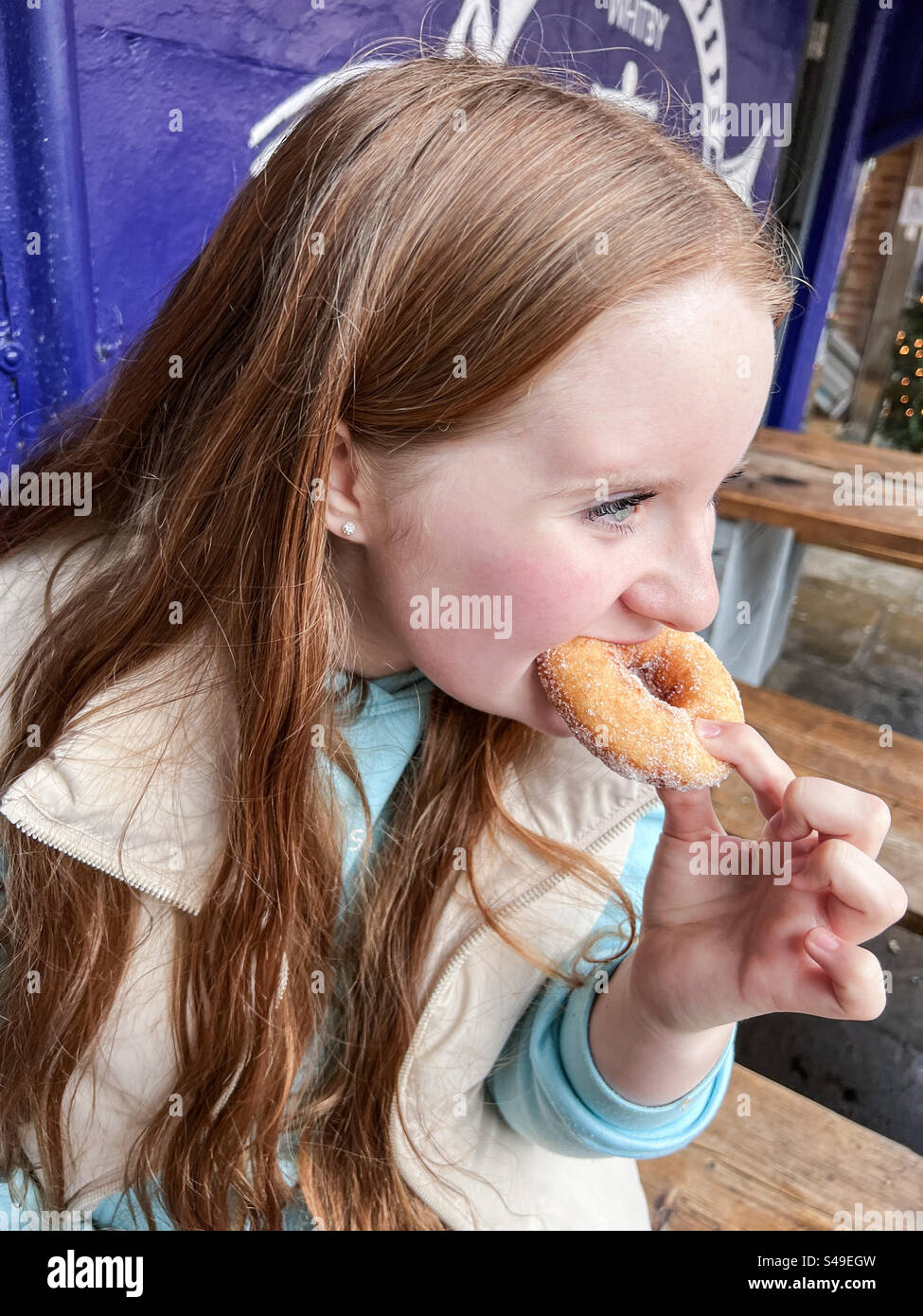 Giovane ragazza che mangia una ciambella allo zucchero Foto Stock