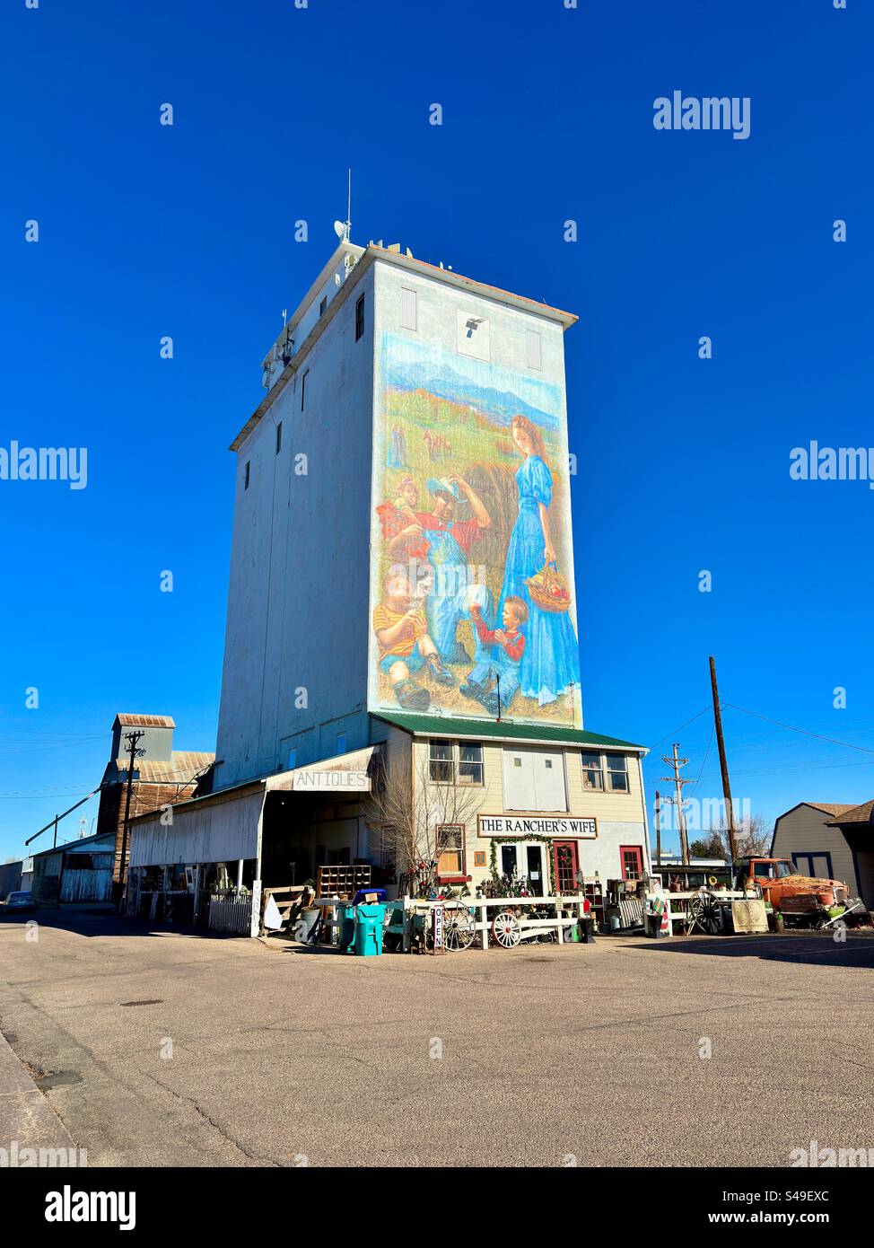 Berthoud, Colorado, Stati Uniti: Veduta della moglie del Rancher, un negozio di antiquariato. Ex ascensore per cereali ed edificio storico situato nel centro città. Murale della famiglia Plains durante un'epoca precedente. Foto Stock