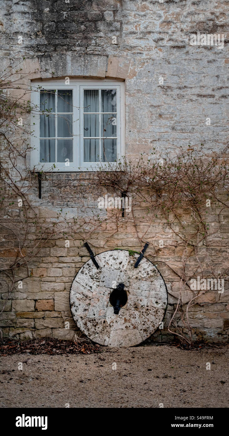 Il vecchio muro e la ruota hanno una storia da raccontare. Foto Stock