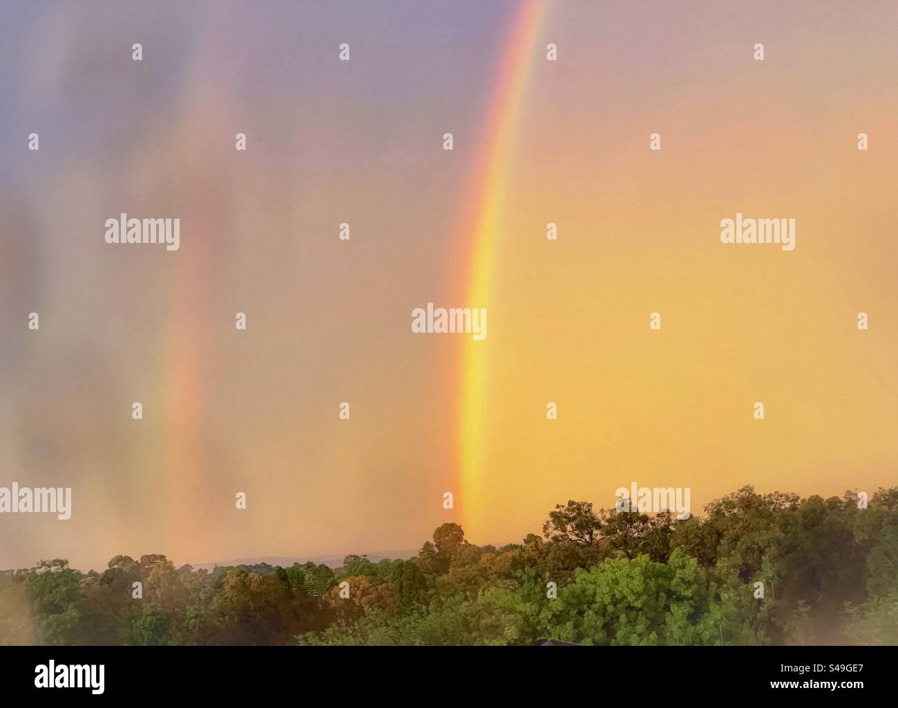 Doppio arcobaleno nel cielo del tramonto dopo la tempesta visto attraverso il vetro bagnato della finestra. Natura panoramica. Orizzontale. Cielo drammatico. Foto Stock