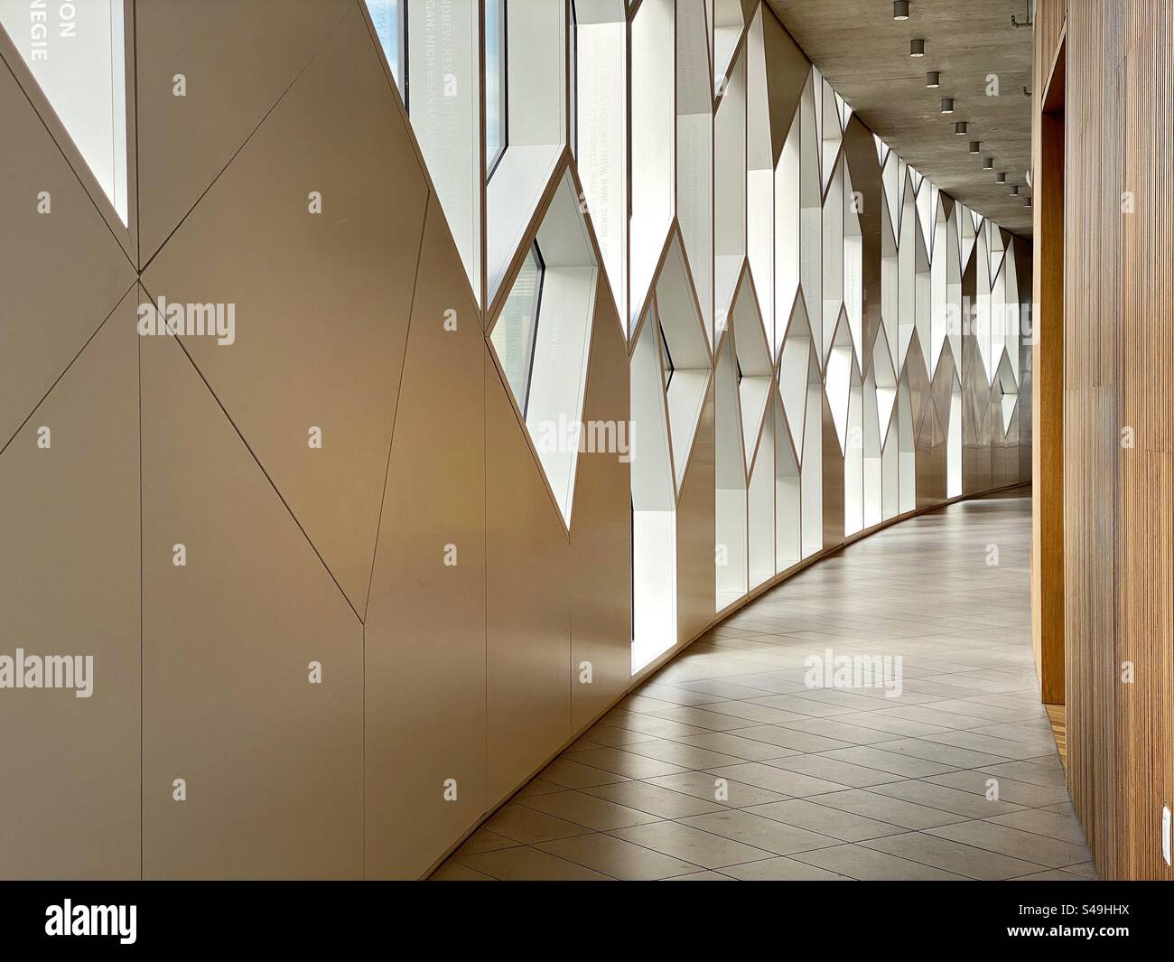 Un corridoio curvo illuminato da interessanti finestre presso la sede principale della Biblioteca pubblica di Calgary. - Immagine stock catturata con smartphone
