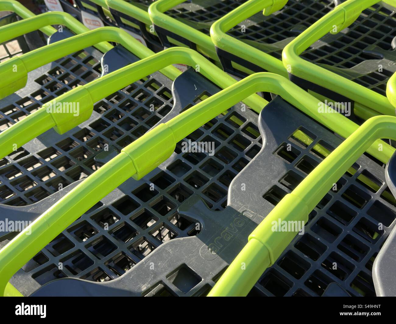Maniglie del carrello per supermercati in plastica verde brillante all'esterno di un negozio agricolo del Worcestershire - Immagine stock catturata con smartphone