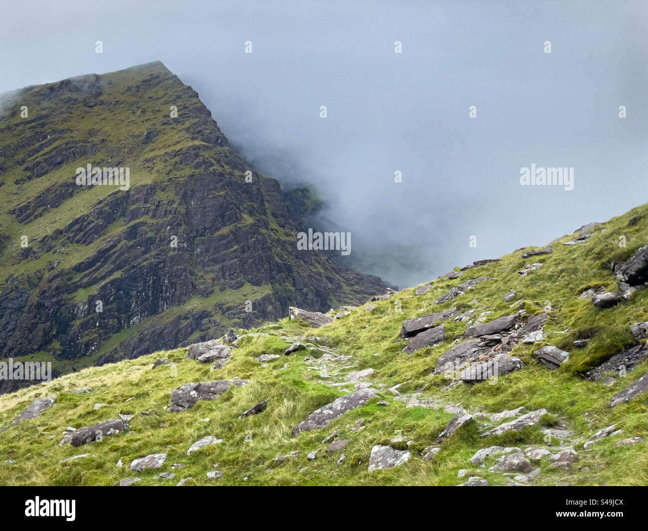 Nuvole e maltempo che si snodano lungo il percorso a piedi fino al Monte Brandon dal parcheggio Fafa, Cloghane, penisola di Dingle, Irlanda - Immagine stock catturata con smartphone