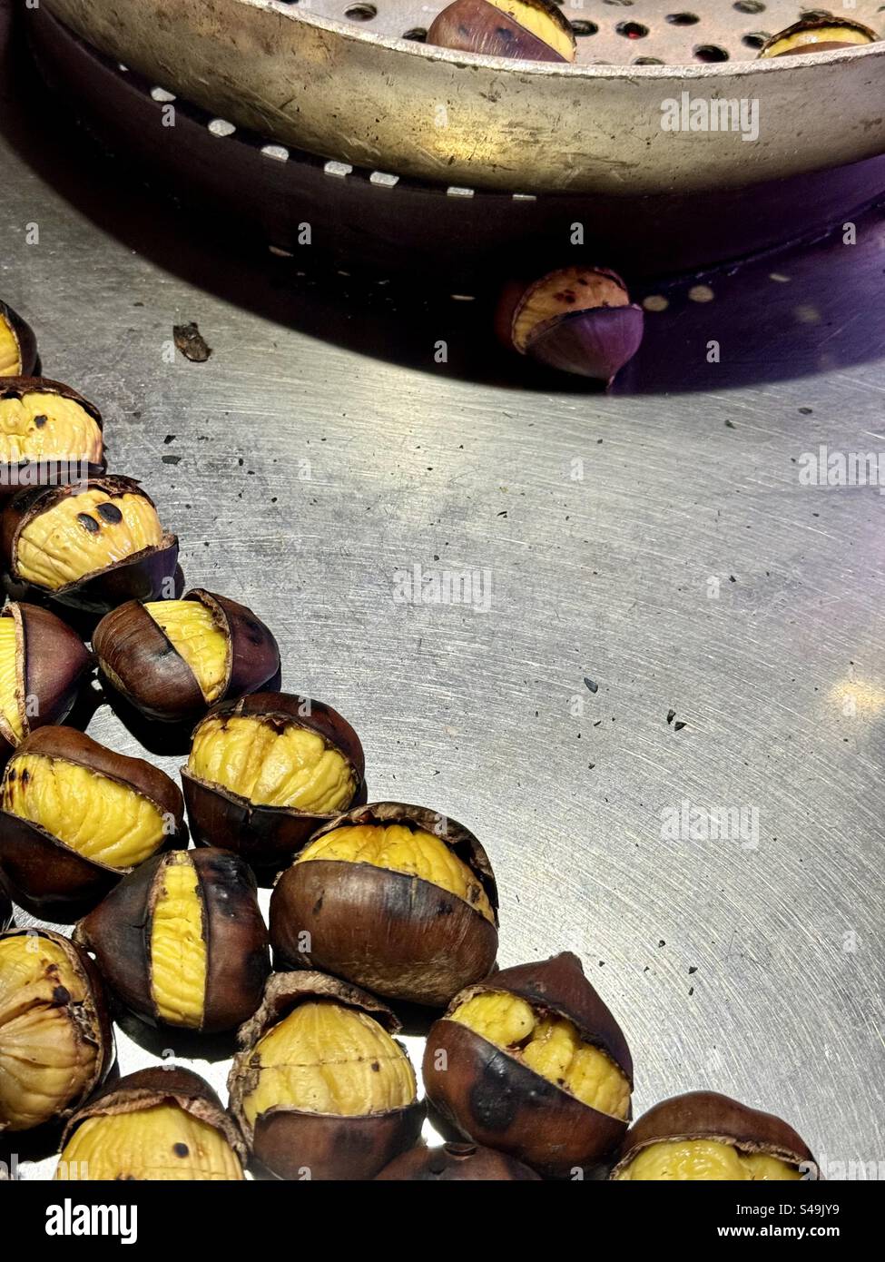Castagne appena tostate in una tradizionale teglia perforata in una bancarella di cibo di strada ad Atene, Grecia - Immagine stock catturata con smartphone
