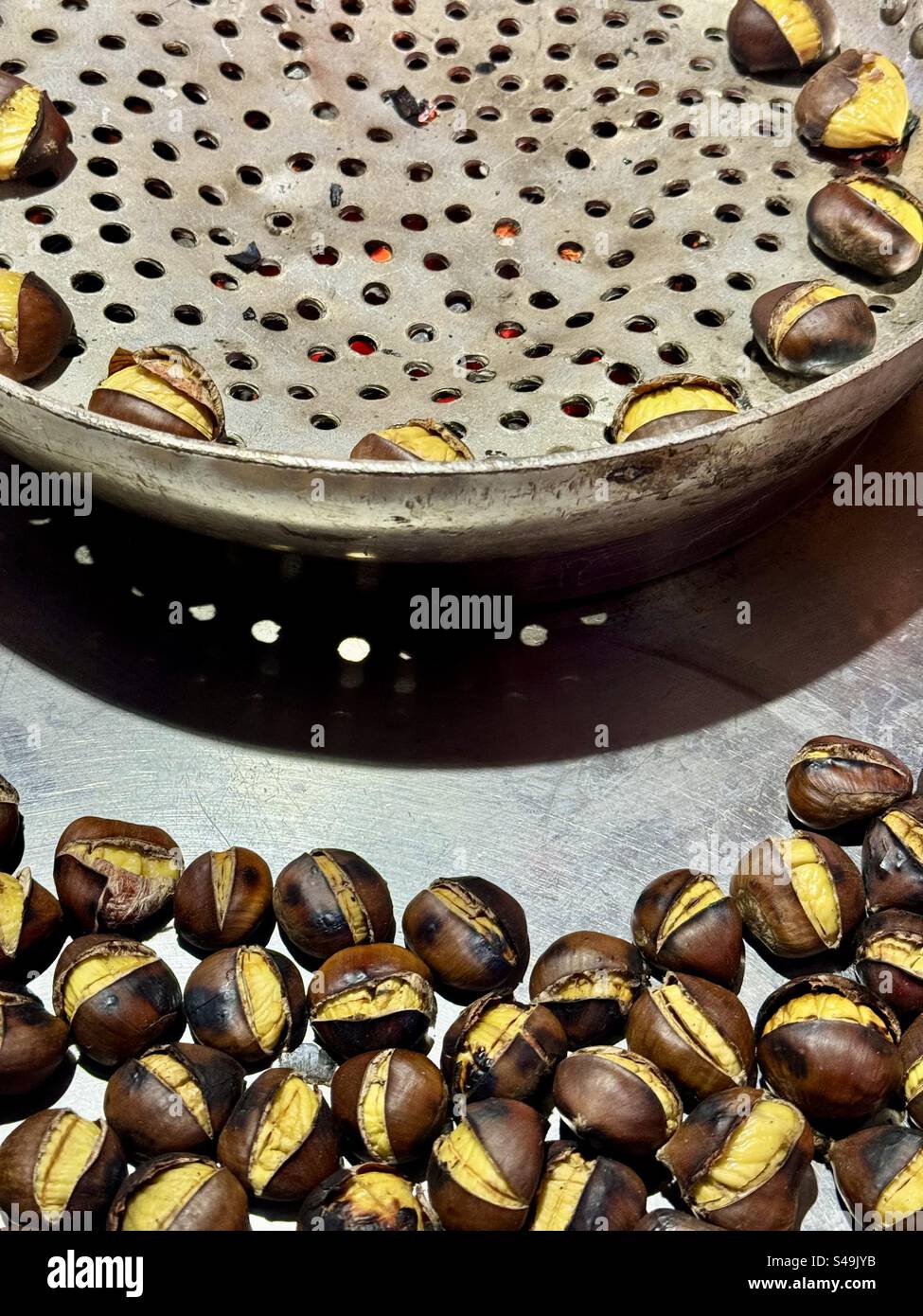 Castagne appena tostate in una tradizionale teglia perforata in una bancarella di cibo di strada ad Atene, Grecia - Immagine stock catturata con smartphone