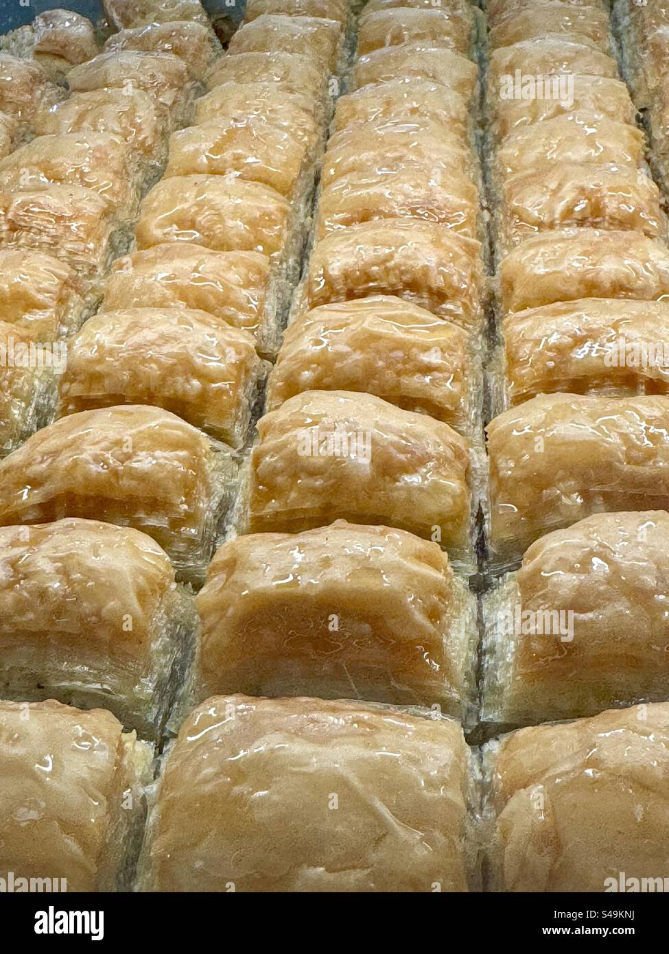Dolci tradizionali greci appena sfornati disposti ordinatamente in file, luccicanti con sciroppo. Tradizionale da Atene, Grecia - Immagine stock catturata con smartphone