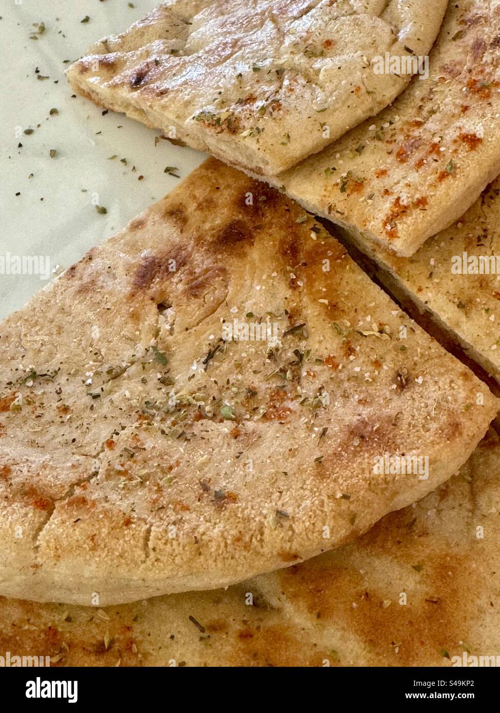 Primo piano di pane pita greco tradizionale appena sfornato cosparso di erbe aromatiche. - Immagine stock catturata con smartphone