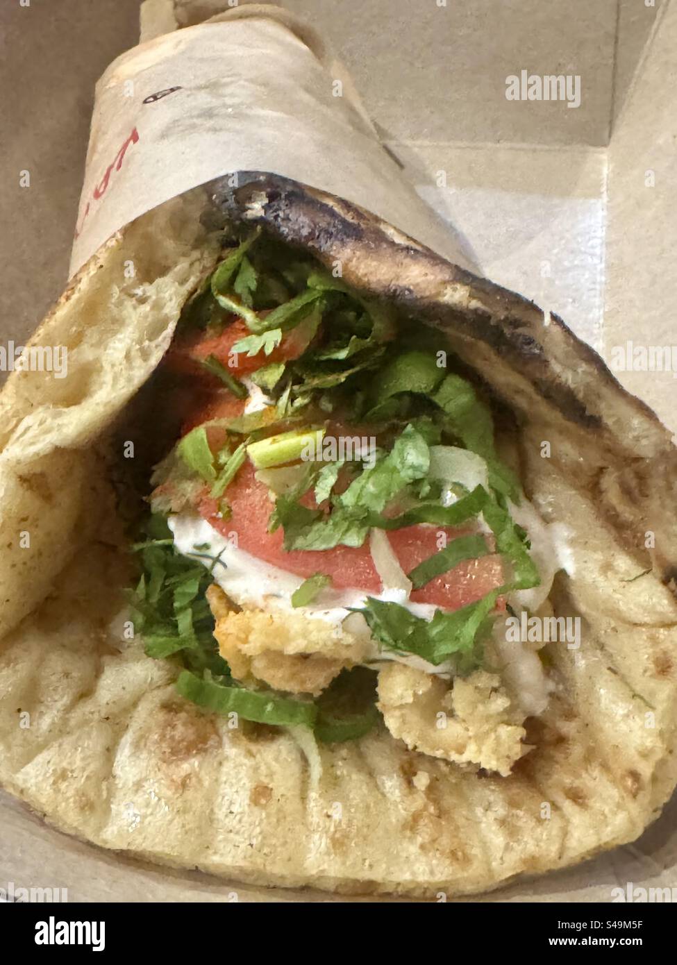 Questa prelibatezza si chiama GYRO ad Atene, in Grecia. È un “wrap” con pane Pita e questo è con calamari Questa prelibatezza può essere fatta anche con maiale, manzo, pollo, ecc. - Immagine stock catturata con smartphone