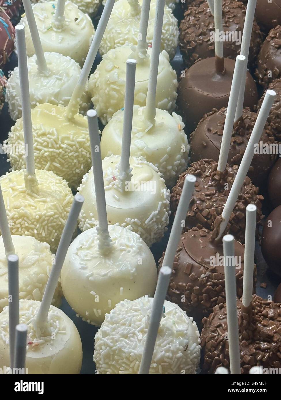 Primo piano di dolci assortiti al cioccolato, al cocco e al limone su bastoncini, esposti ad Atene, Grecia. - Immagine stock catturata con smartphone