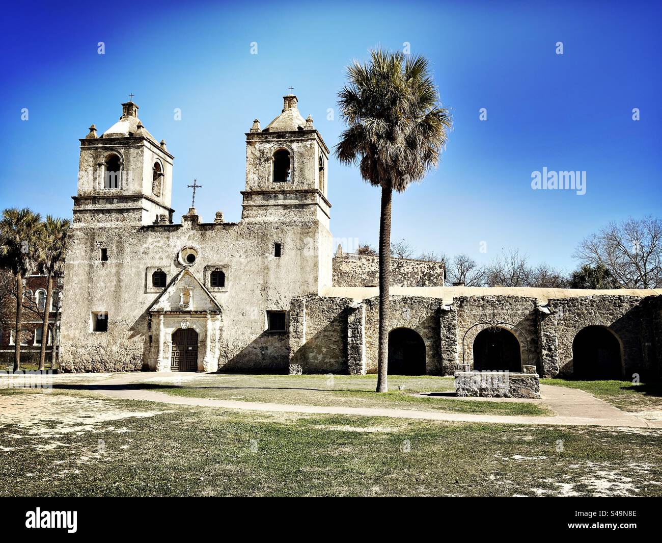 Missione Concepcion al San Antonio Missions National Historical Park in Texas, Stati Uniti. Palma davanti all'erba. Sito patrimonio dell'umanità dell'UNESCO. La più antica chiesa in pietra non restaurata d'America. - Immagine stock catturata con smartphone