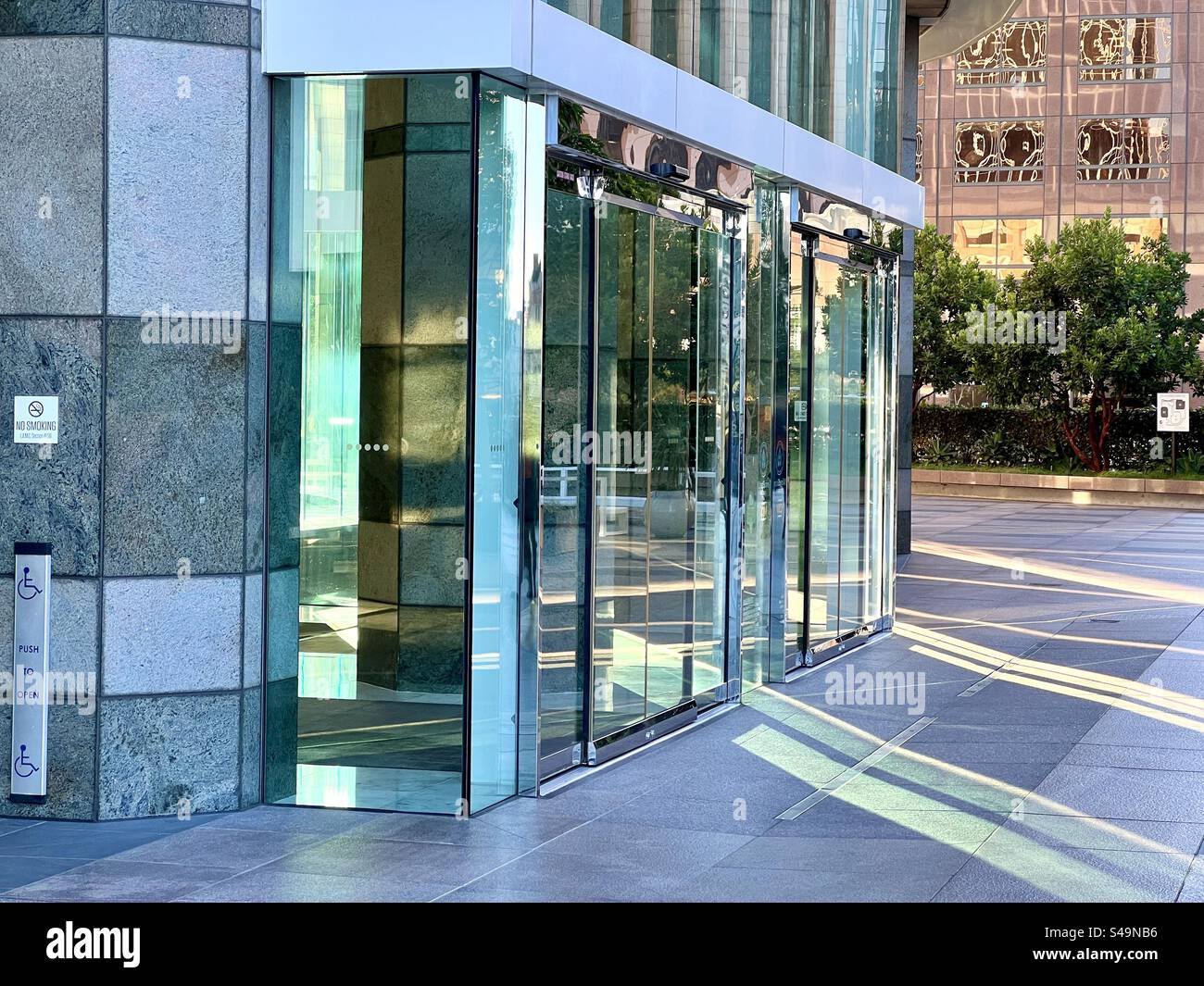 LOS ANGELES, CA, 5 agosto 2023: La luce del sole del tardo pomeriggio splende attraverso le finestre colorate di un edificio per uffici nel centro città, creando lunghi raggi di luce verde sul terreno - Immagine stock catturata con smartphone