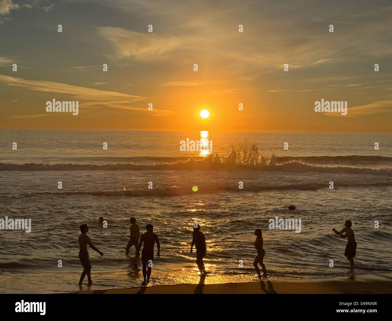 Gli adolescenti giocano tra le onde su una spiaggia di Malibu al tramonto a metà inverno. Lo stile di vita della California a Los Angeles! - Immagine stock catturata con smartphone