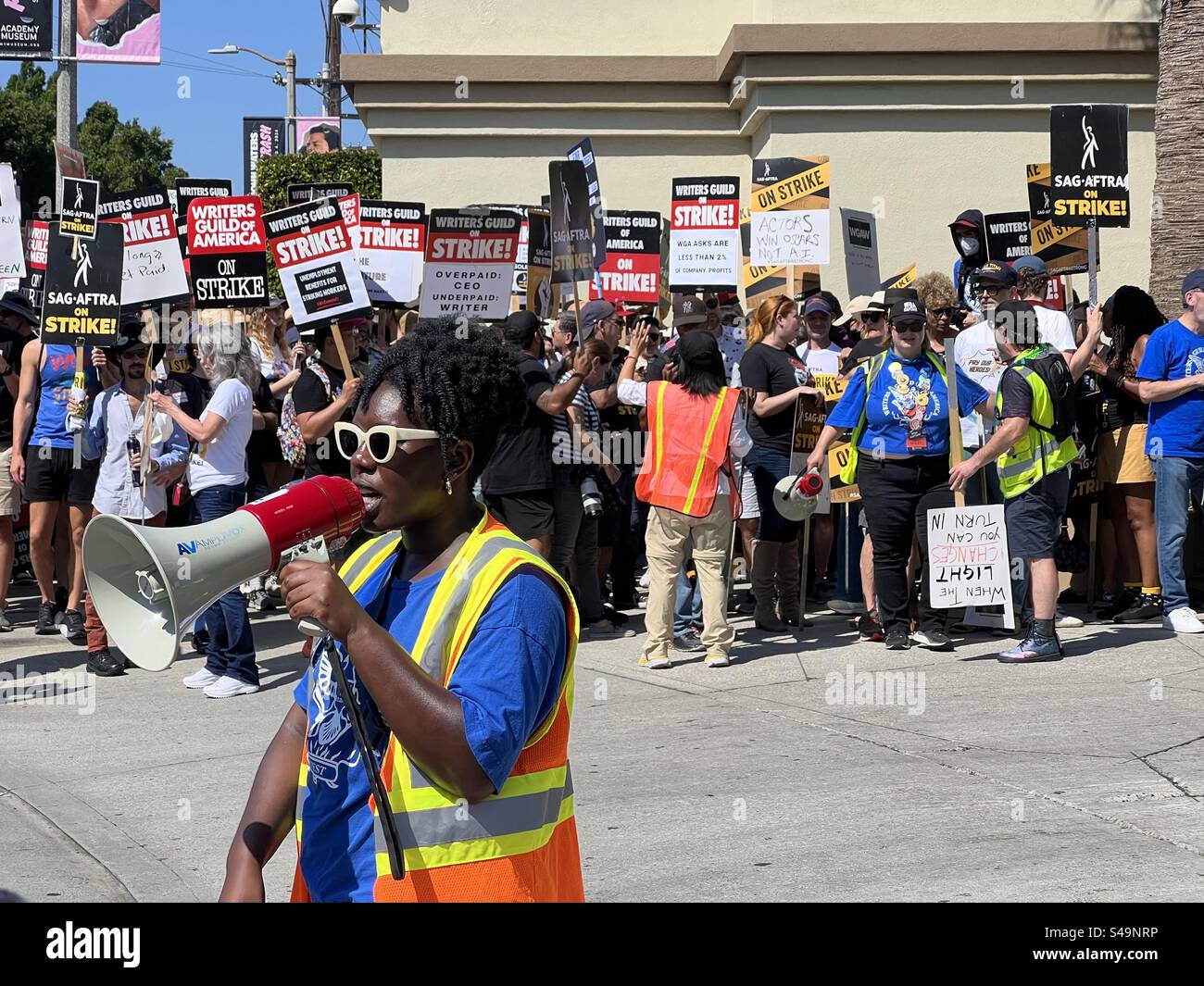 LOS ANGELES, CALIFORNIA, settembre 8, 2023: Membro sindacale con corno di toro continua a colpire i membri WGA e SAG-AFTRA al sicuro, mentre il traffico passa la linea di picchetto fuori dai cancelli della Paramount Studios di Hollywood - Immagine stock catturata con smartphone