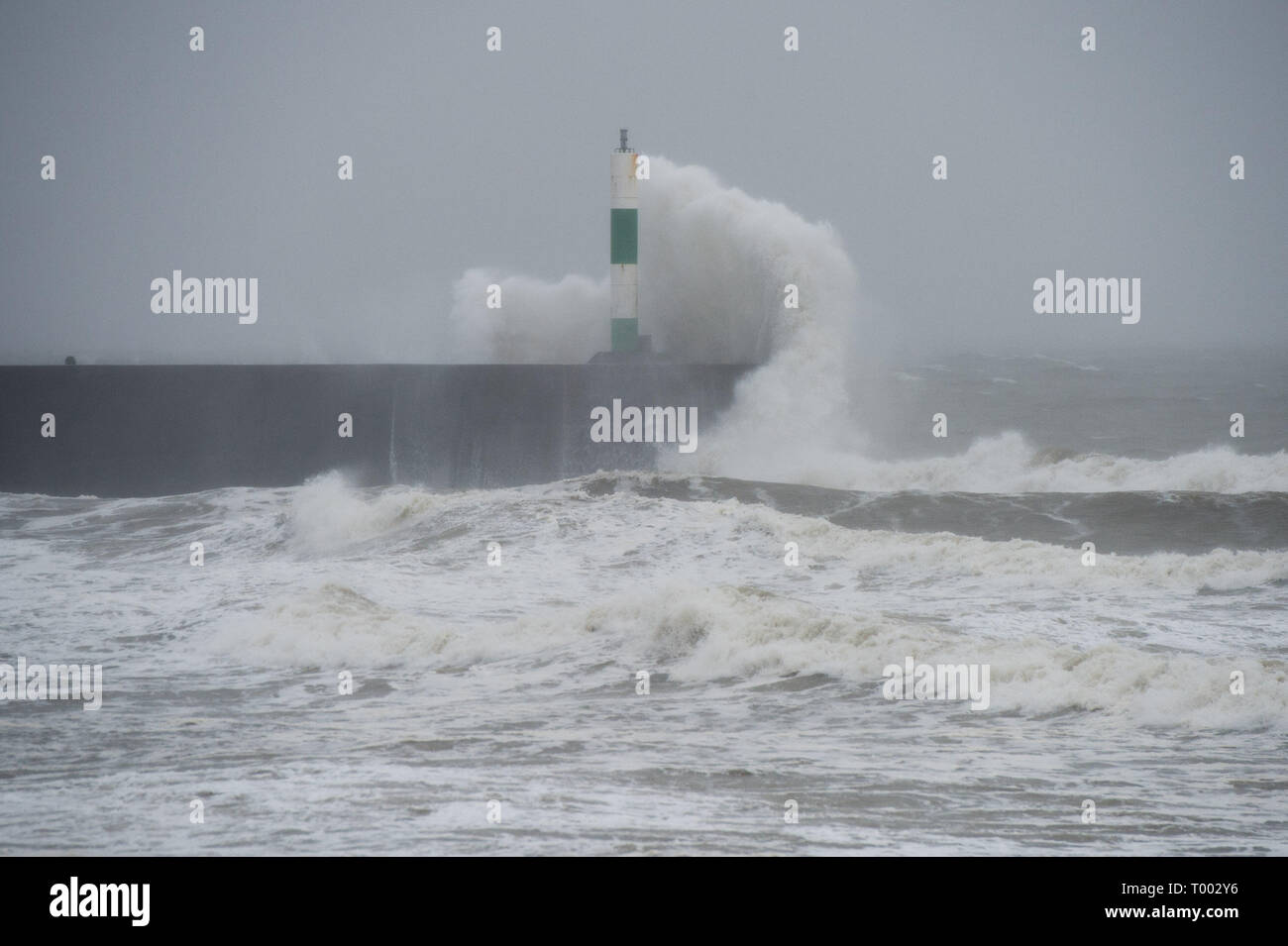 Aberystwyth Regno Unito 16/03/2019 UK Meteo: Storm Hannah offre enormi onde che si infrangono nel faro del porto e le difese del mare su un estremamente bagnato e ventoso giorno in Aberystwyth Wales. Raffiche di oltre 50mph sono previsioni di impatto delle parti il nord e l ovest del paese oggi come il periodo di molto le perturbazioni atmosferiche continua a dominare il Regno Unito Photo credit: Keith Morris/Alamy Live News Foto Stock