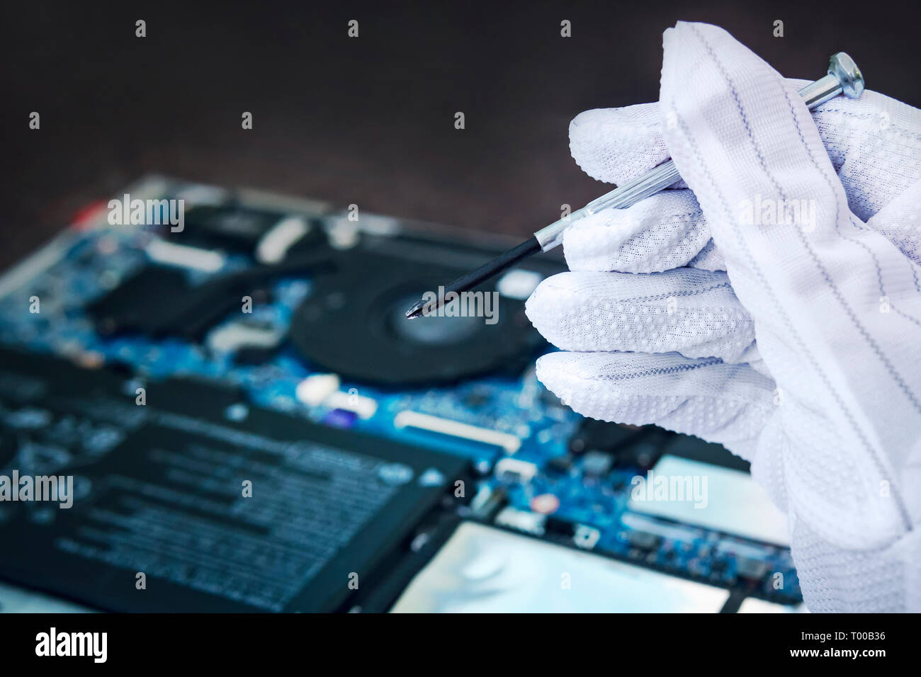 Fissaggio ingegnere computer rotto al lavoro. Tecnico IT riparazione rotto laptop computer notebook. Computer riparazione elettronica concetto di shop. mano in una w Foto Stock