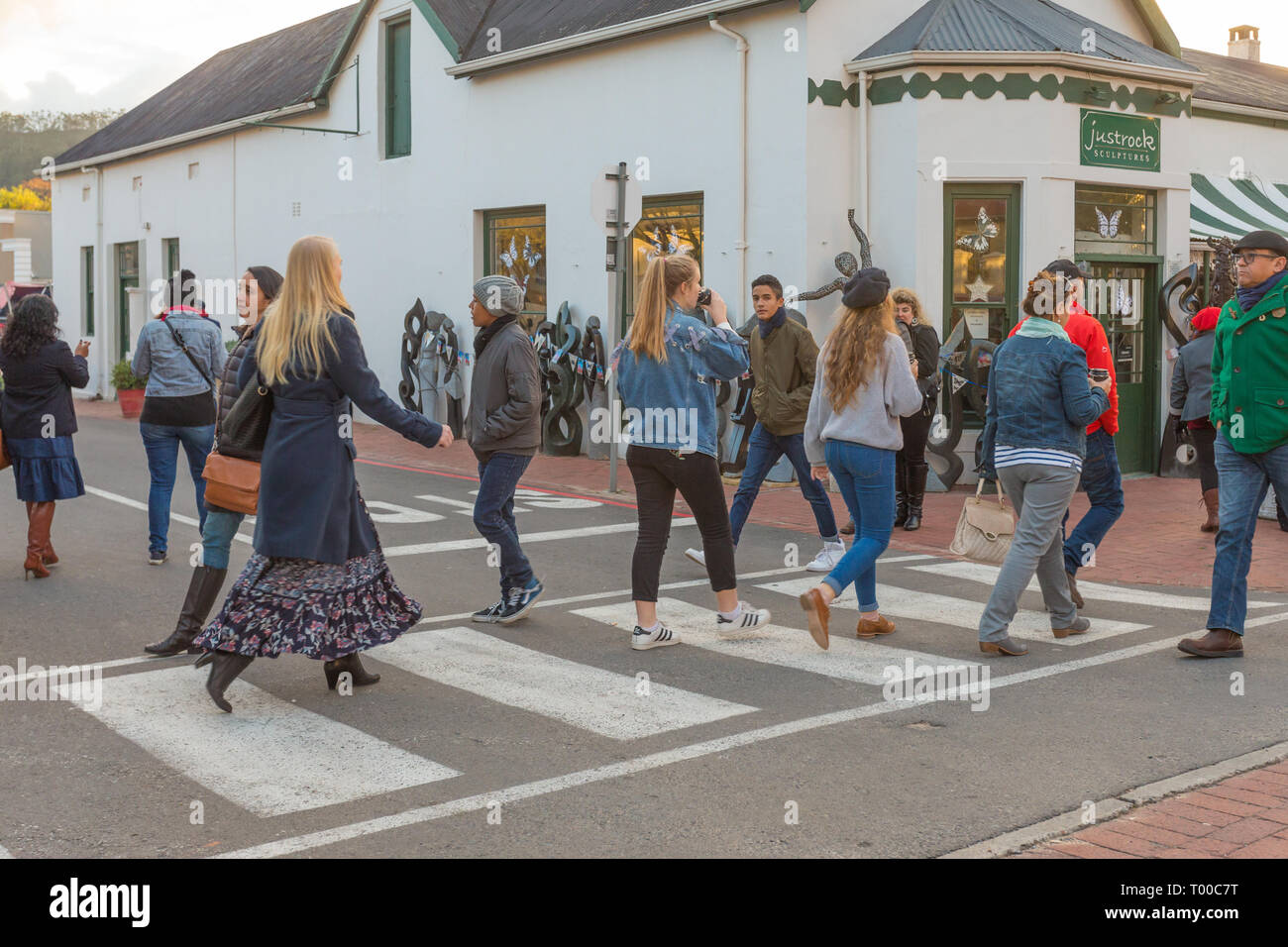 I pedoni o le persone che attraversano la strada a una zebra crossing in Franschhoek village in una fredda giornata invernale Cape Winelands, Sud Africa Foto Stock