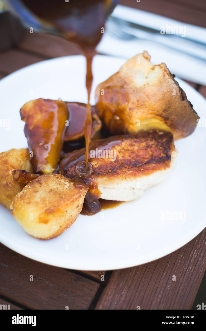 Pollo arrosto cena con Yorkshire pudding. Il sugo di carne che viene versato sopra la parte superiore Foto Stock