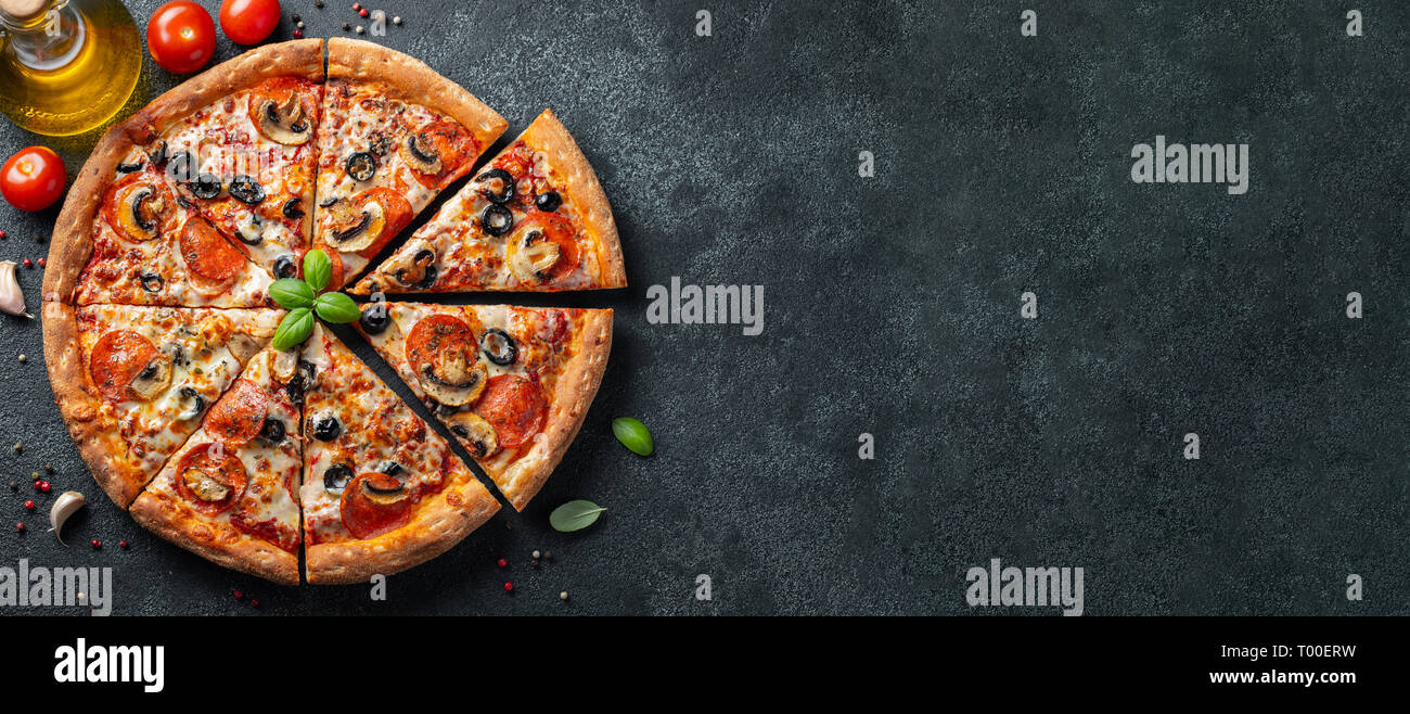 Gustosa salsiccia per pizza pizza con funghi e olive nere su sfondo di calcestruzzo. Vista superiore della salsiccia per pizza calda pizza. Copia con spazio per il testo. Lay piatto. Divieto Foto Stock