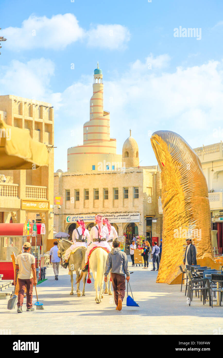 Doha, Qatar - 20 Febbraio 2019: due funzionari di polizia a cavallo bianco cavallo arabo al Souq Waqif. Fanar Centro Culturale Islamico con moschea a spirale e Foto Stock