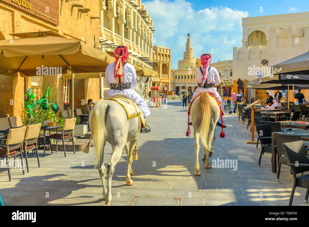 Doha, Qatar - 20 Febbraio 2019: il patrimonio degli ufficiali di polizia nei tradizionali 1940s Qatar uniforme al vecchio Souq Waqif cavalcare cavalli arabi. Fanar Islamic Foto Stock