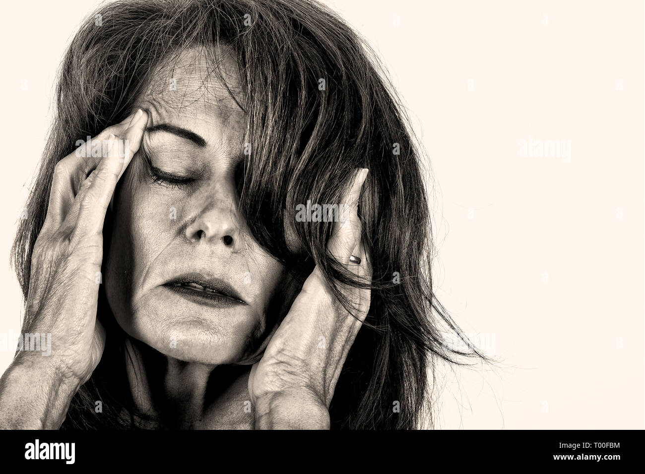 Immagine in bianco e nero di una donna matura tenendo le mani sulla testa del dolore. Foto Stock