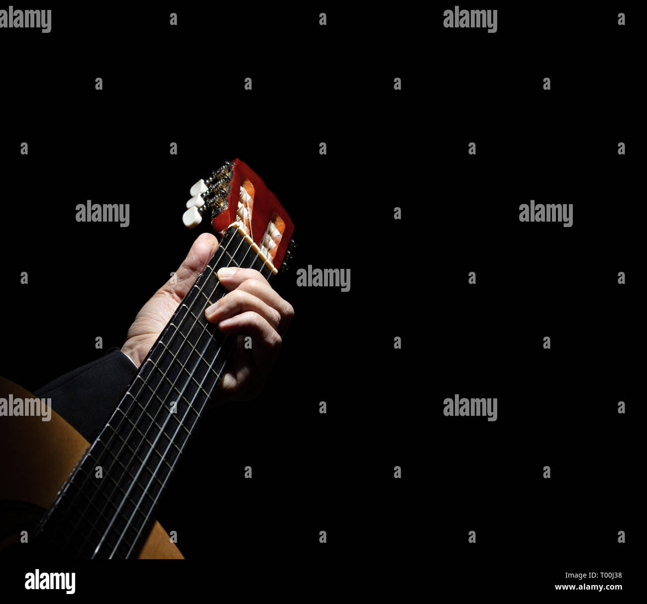 Chiudere con una mano suonare la chitarra spagnola su sfondo nero. Foto Stock